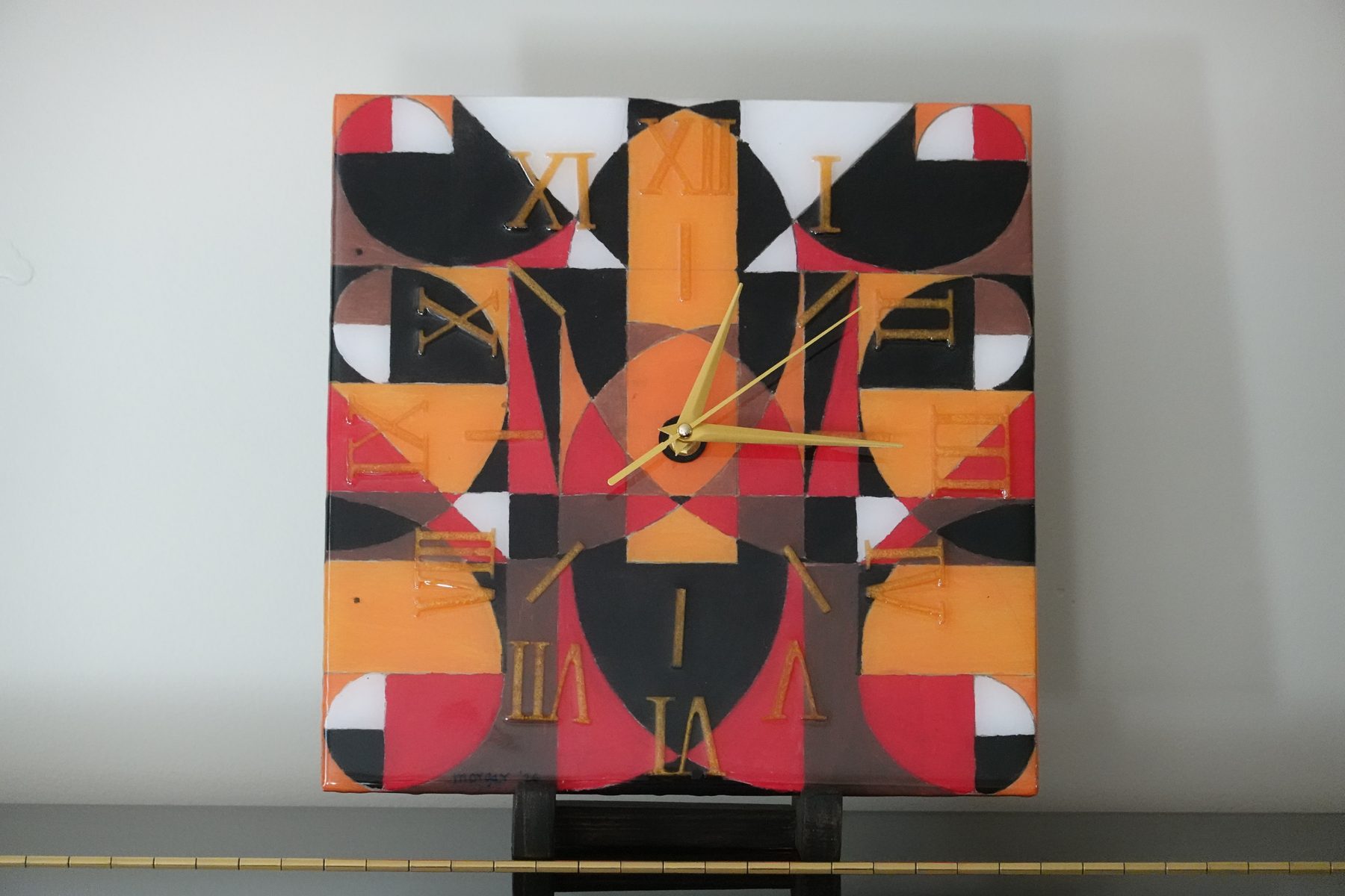 Solar Fragment clock, an angular abstract painted resin clock in orange, black and red