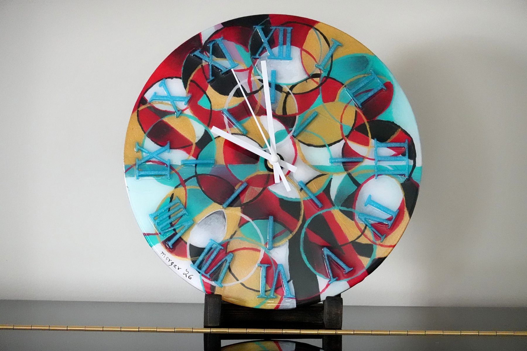 Orbit Study clock, a circular abstract painted resin clock with overlapping circles in red, teal, gold and black